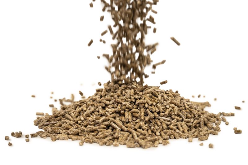 Holzpellets fallen auf einen Haufen Holzpellets