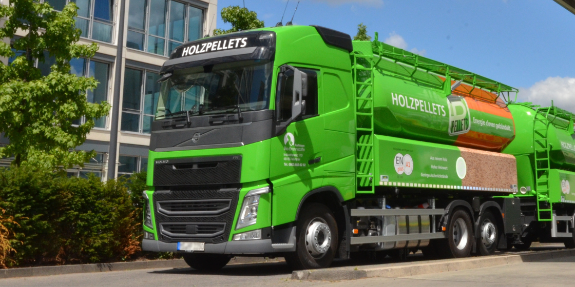 Silofahrzeug für die Auslieferung von Holzpellets auf einer Straße vor einem Bürogebäude. Der Pellet-Lkw ist mit mehreren Kammern für den Transport von Holzpellets ausgestattet.